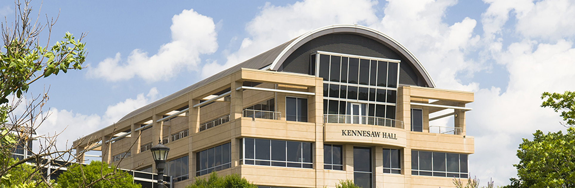 A large, modern building with a curved roof and the name 'Kennesaw Hall' displayed prominently