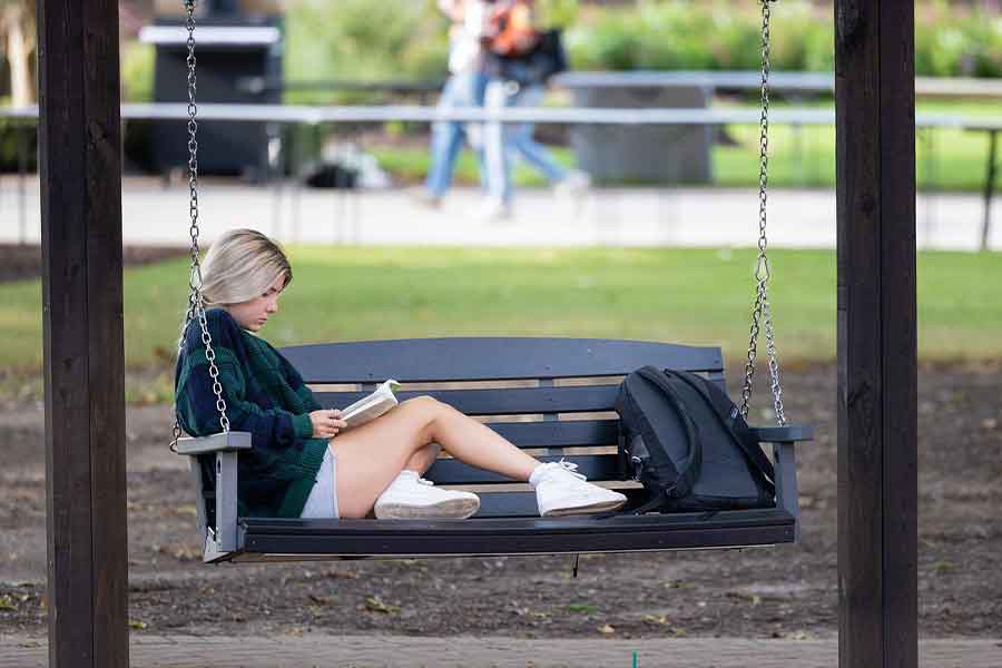 first-gen student on campus studying on swing.