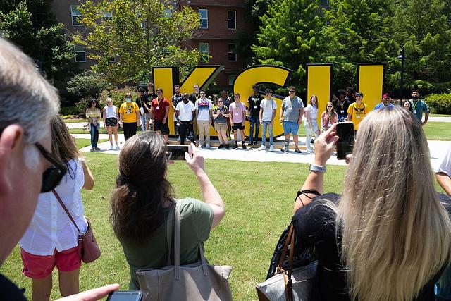 Family taking pictures of students in front of the KSU sign