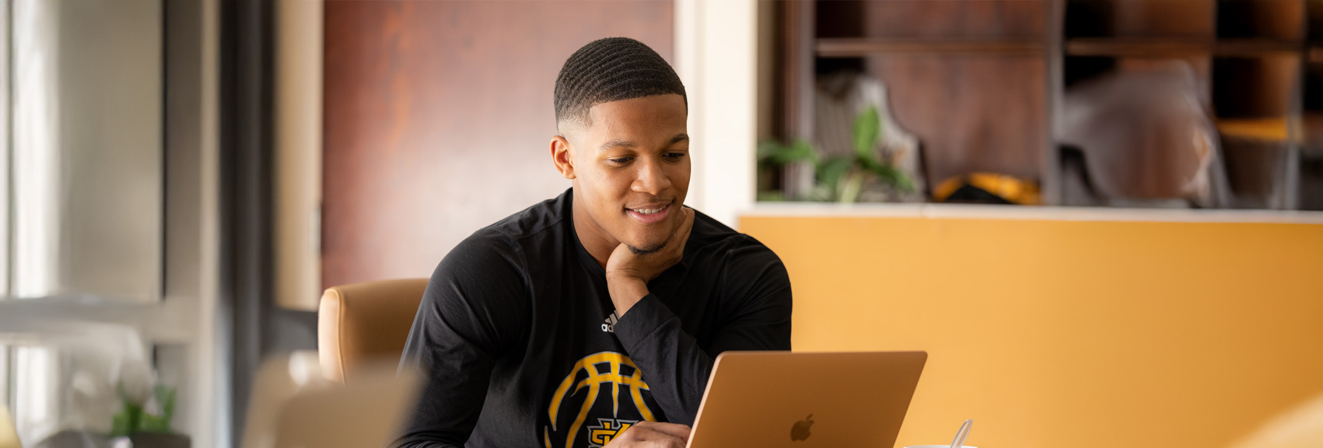 man sitting at a table with mac laptop