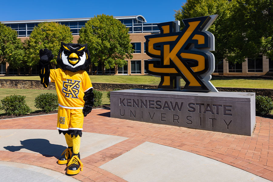 scrappy standing in front of the ksu statue on campus.