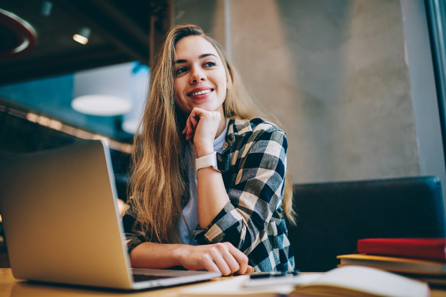 person sitting in front of laptop with chin on hand looking prospectively into distance